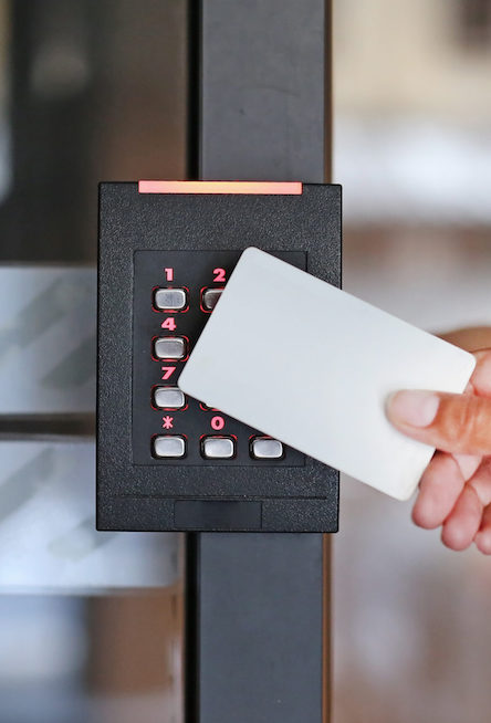 Door access control - young woman holding a key card to lock and unlock door.